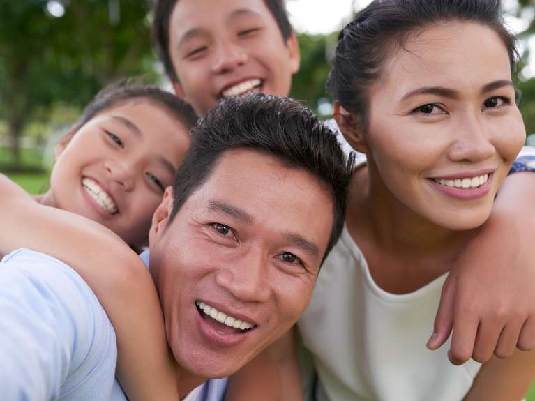 asian family smiling outside | dentist lara